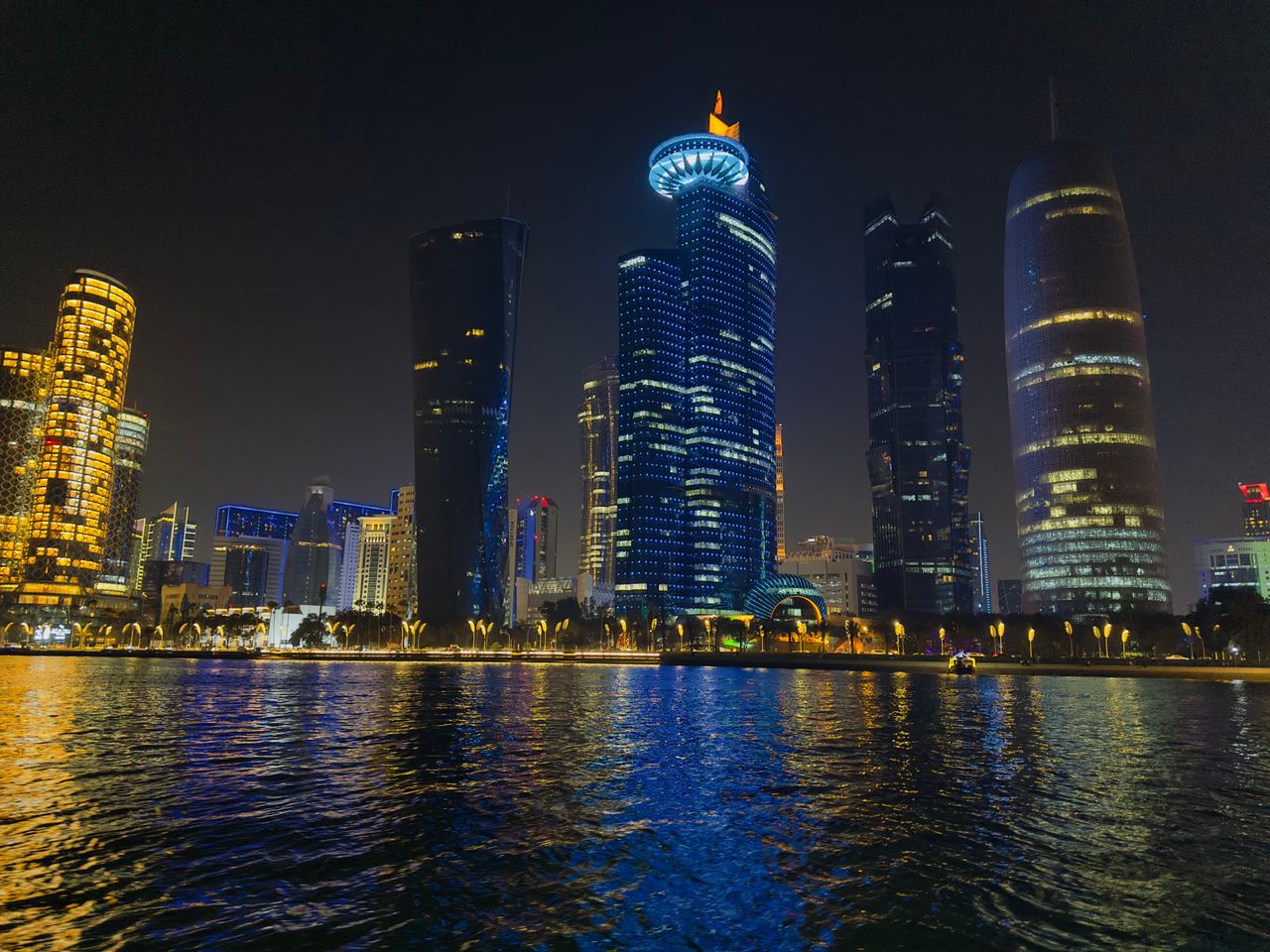 Captivating night scene of Doha's illuminated skyline reflecting on water in Qatar.